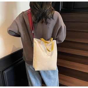 Vue détaillée du sac cabas en toile avec anses jaunes et bandoulière rouge ajustable