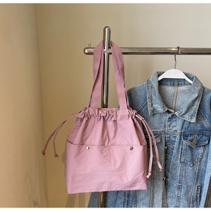 Detail of mauve nylon tote bag featuring drawstring closure and front snap pockets