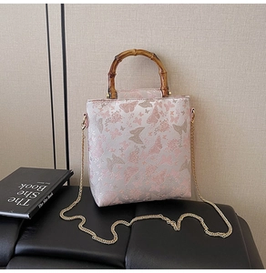 Detail of pink lace handbag with butterfly embroidery and vintage bamboo handle