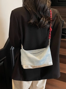 Light blue glitter tote bag with red woven rope strap worn by a model against dark stairs