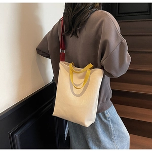Vue lifestyle du sac cabas en toile crème avec poignées jaunes et bandoulière rouge vif