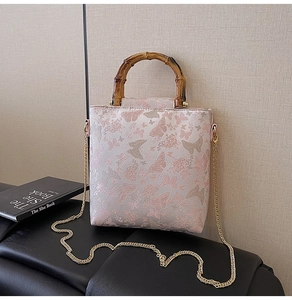 Close-up of jacquard floral handbag with bamboo handle and elegant metal chain strap