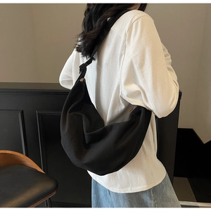 Detail of minimalist black canvas crossbody dumpling bag with wide shoulder strap
