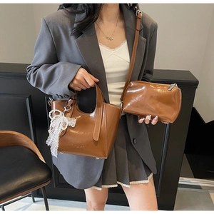 Detail of dark brown glossy bucket bag with fashion print and lace ribbon strap accessory