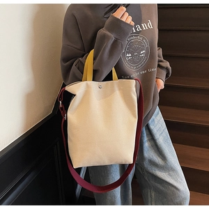 Détail du sac fourre-tout en toile avec poignées jaunes et bandoulière bordeaux