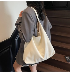 Close-up of a large white glossy tote bag showing the seamless minimalist shoulder strap