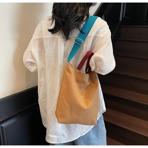 Détail du sac fourre-tout en toile avec bandoulière bleue et poignée bordeaux sur mannequin