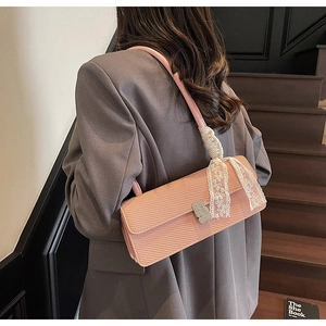 Dettaglio della borsa in pelle rosa con fibbia di strass e nastro di pizzo bianco