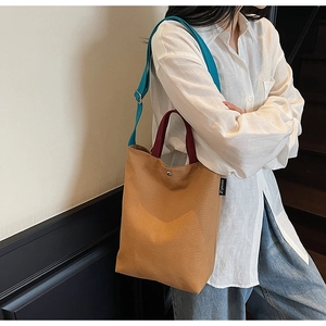 Détail du sac seau en toile montrant les anses colorées et la bandoulière réglable