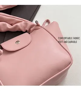 Close-up of pink pleated handbag showing soft texture and silver cylindrical metal buckle