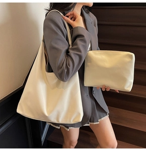 Detail view of large minimalist cream tote bag with matching zippered pouch on shoulder