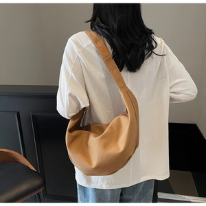 Brown canvas crescent bag shown on model highlighting the minimalist aesthetic and size