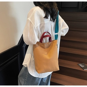 Vue détaillée du sac cabas en toile avec poignées bordeaux et bandoulière bleue