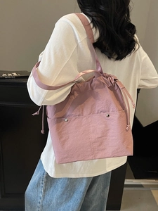 Lotus pink drawstring bucket bag with dual front pockets and woven shoulder strap