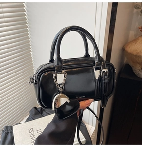 Close-up of black patent leather boston bag with silver hardware and heart charm