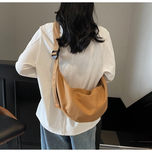 Detail of khaki canvas crescent bag with adjustable wide strap shown on a model
