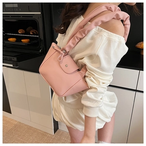 Detail of pink PU leather shoulder bag featuring pleated cloud strap and magnetic front pocket