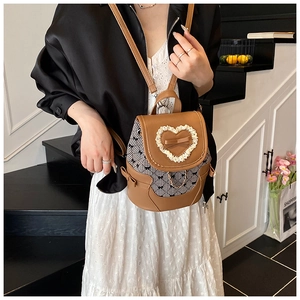 Detail of fashion bow backpack with heart lace and gold chain on leather and plaid fabric