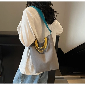 Détail du sac cabas en toile grise avec poignée jaune et bandoulière bleue vive