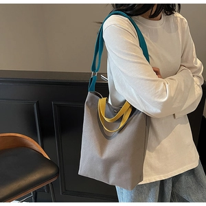 Détail du cabas en toile grise avec bandoulière bleue et poignées jaunes vives