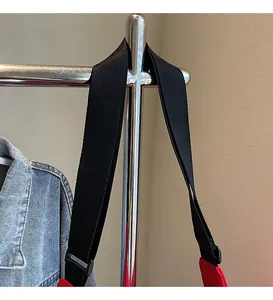 Detail of adjustable black wide nylon shoulder strap on a red canvas crossbody bag