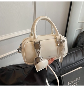 Macro shot of cream Boston bag with silver heart charm and detailed brand lettering