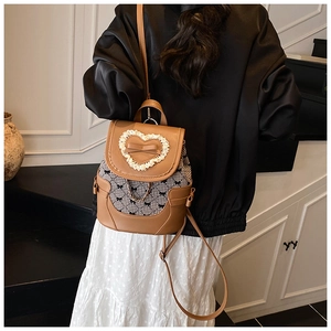 Detail of a brown leather and plaid backpack with lace heart and golden chain