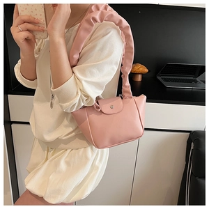 Detail of pink shoulder bag featuring decorative pleated handle and flap closure with snap