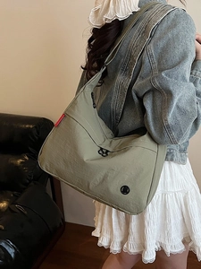Olive green high-density nylon crossbody tote bag shown on model in cozy indoor setting