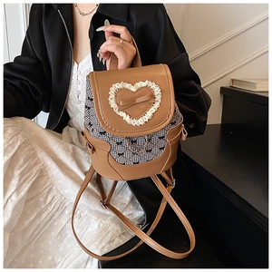 Detailed shot of bow knot and lace heart decor on a vintage brown plaid backpack