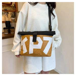 Detail view of water-resistant tan sling bag with KP7 letter print worn by model