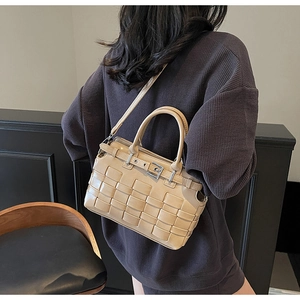Dettaglio della borsa a secchiello intrecciata beige con fibbia e manico rotondo