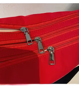 Detailed close-up of three smooth metal zippers on a red nylon crossbody bag