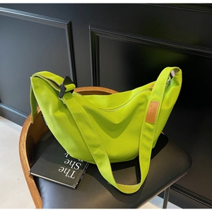 Detail of neon green canvas crescent shoulder bag featuring adjustable strap and logo patch