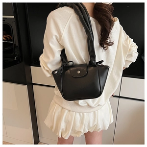 Detail of a black pleated shoulder bag with twisted handles and metallic buckle