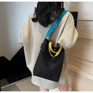 Détail d'un sac cabas en toile bicolore avec bandoulière bleue et poignée jaune design