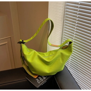 Detail of neon green nylon crescent bag with brown leather accents on black sofa