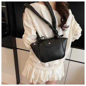 Detail of black faux leather shoulder bag featuring silver buckle and pleated strap