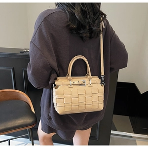 Vista laterale di una borsa a tracolla intrecciata kaki con fibbia su una modella