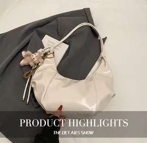 Detail showing creamy white pleated faux leather shoulder bag with plush bear charm