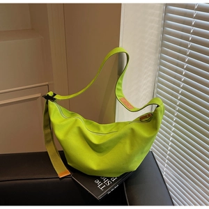 Detail of lime green canvas crescent bag with adjustable strap and leather logo tag