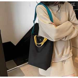 Détail d'un sac cabas en toile bicolore avec bretelles réglables porté par un mannequin