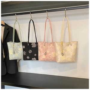Detail showing high-density floral jacquard fabric and metal charm on four bucket bags