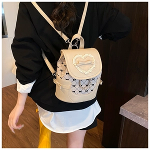 Detail of beige bow backpack with heart lace and plaid pattern worn by a model