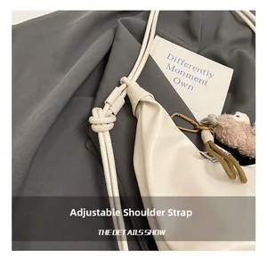Detail of adjustable knotted shoulder strap on a white pleated crescent dumpling bag
