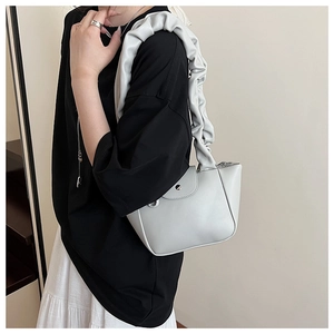 Detail of grey pleated shoulder bag with scrunchie strap and minimalist metal clasp