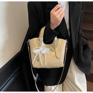 Detail of apricot patent leather bucket bag with lace bow and pearl bead charms