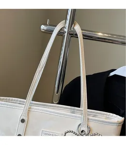 Detail der weißen Leder-Tote-Bag mit silbernen Nieten und modischem Perlenanhänger-Zubehör