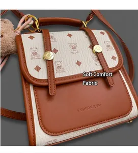 Detailed view of the brown leather and logo print fabric with a plush bear charm
