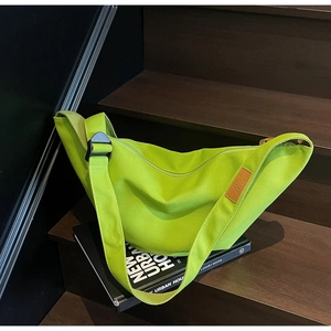 Detail of neon green canvas crossbody bag with branded patch on wooden stairs